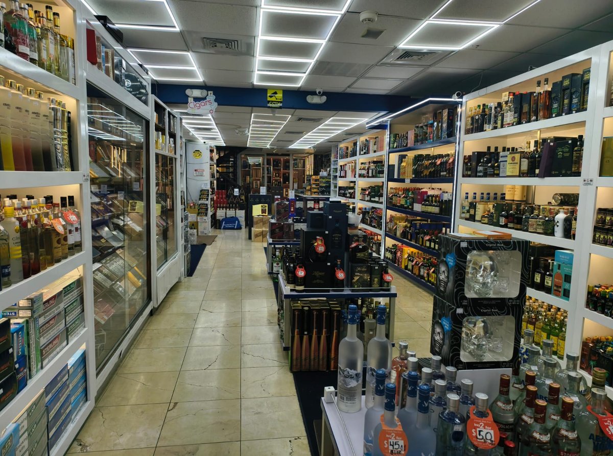Interior of a convenience or liquor store with shelves of products lining both sides and overhead lighting