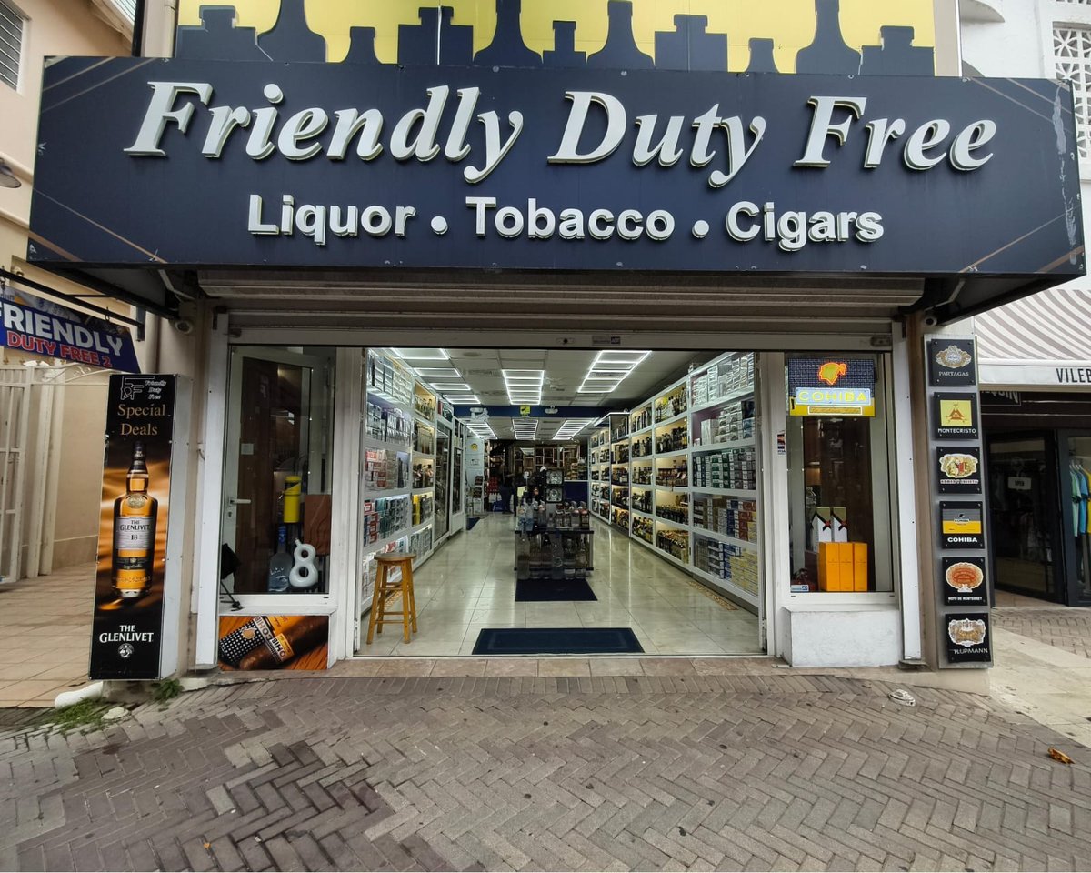 Friendly Duty Free storefront displaying liquor, tobacco, and cigars with glass windows and dark blue signage