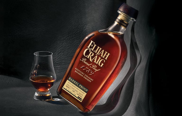 Elijah Craig bourbon bottle next to a glass of whiskey on a dark textured background