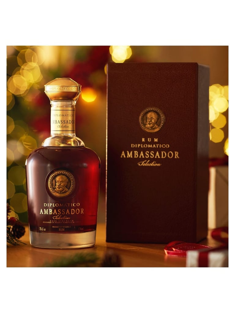 Diplomático Rum Ambassadorotten bottle with matching brown gift box displayed against warm bokeh lights