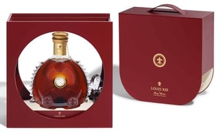 Luxury cognac bottle displayed in elegant burgundy packaging box with gold emblem and presentation window